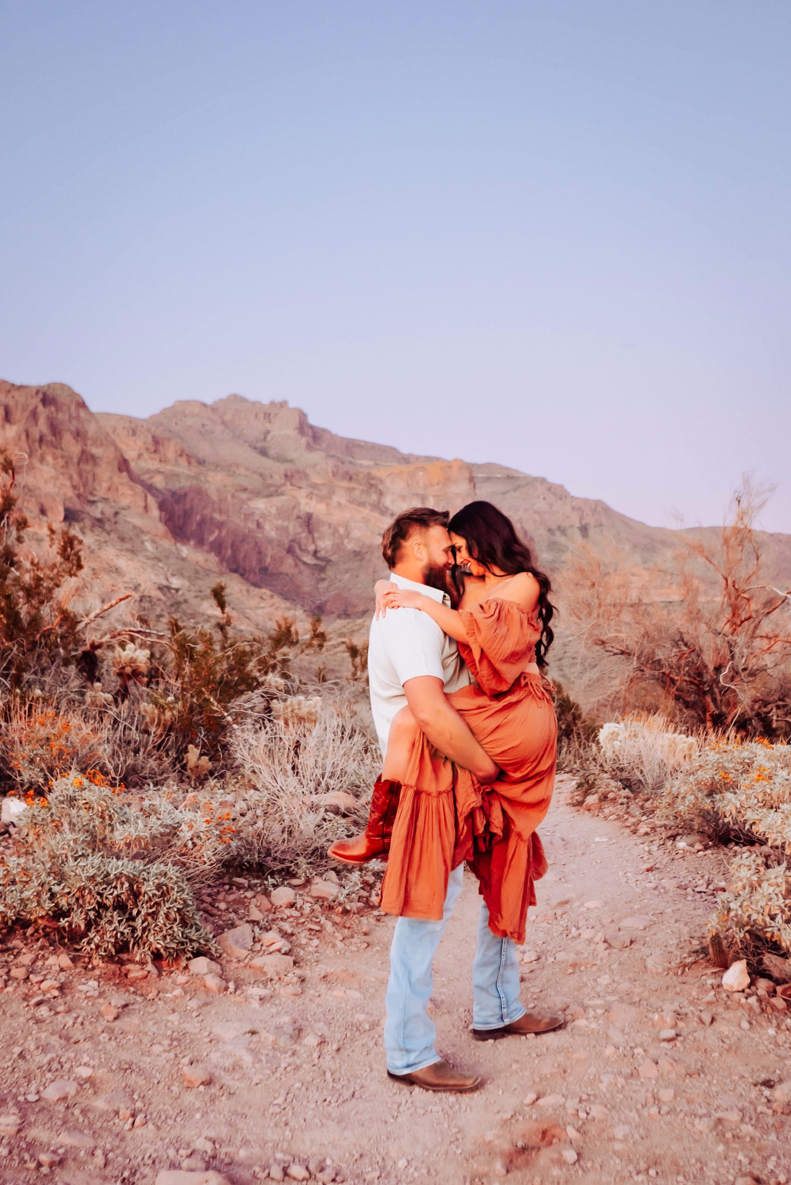 Jason and Kiana of United by Design embracing on a desert trail at golden hour